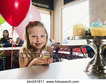 Stock Image - Caucasian girl celebrating birthday in cafe. Fotosearch