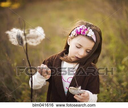 Stock Photograph - Caucasian girl examining plants outdoors. Fotosearch