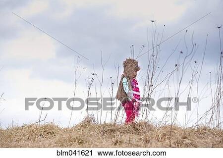 Stock Image - Caucasian girl walking on hilltop. Fotosearch