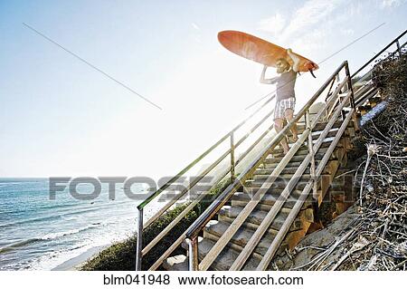 Caucasian man carrying surfboard on stairs at beach View Large Photo Image Stock Photo - Caucasian man carrying surfboard on stairs at beach. Fotosearch