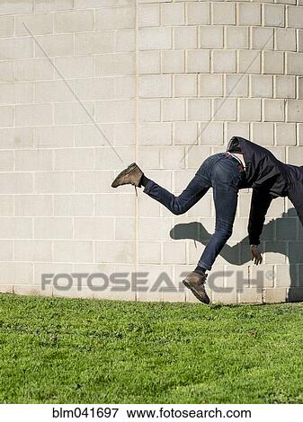 Caucasian man falling near brick wall View Large Photo Image Stock Photo - Caucasian man falling near brick wall. Fotosearch