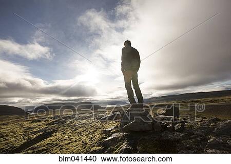 Caucasian man standing on rock in field View Large Photo Image Stock Image - Caucasian man standing on rock in field. Fotosearch