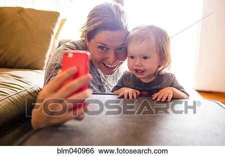 Stock Photograph - Caucasian mother and baby daughter taking selfie. Fotosearch