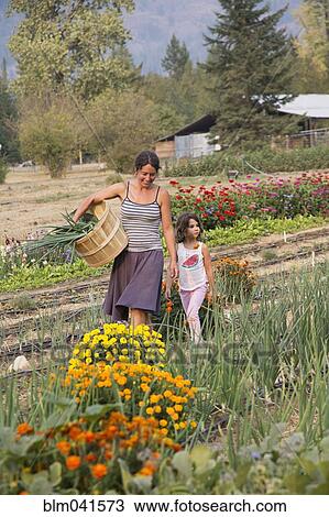 Stock Image - Caucasian mother and daughter walking in garden. Fotosearch