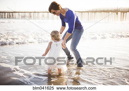 Stock Photography - Caucasian mother and daughter walking on beach. Fotosearch
