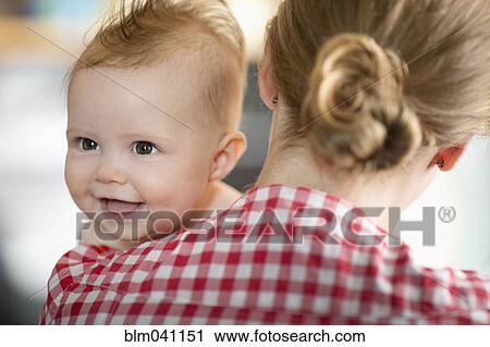 Stock Image - Caucasian mother carrying baby daughter. Fotosearch