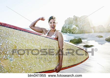 Caucasian surfer flexing muscle at beach View Large Photo Image Stock Photography - Caucasian surfer flexing muscle at beach. Fotosearch