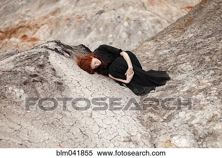 Stock Photography - Caucasian woman laying on rock formation. Fotosearch