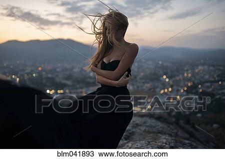 Stock Image - Caucasian woman on hilltop near cityscape view. Fotosearch
