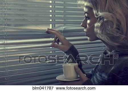 Stock Photo - Caucasian woman peering through blinds. Fotosearch