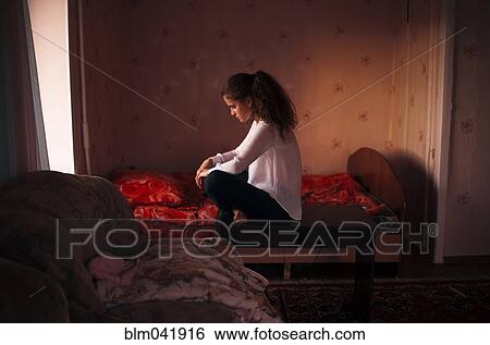 Stock Photograph - Caucasian woman sitting in bedroom. Fotosearch