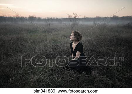 Caucasian woman sitting in remote field View Large Photo Image Stock Photo - Caucasian woman sitting in remote field. Fotosearch