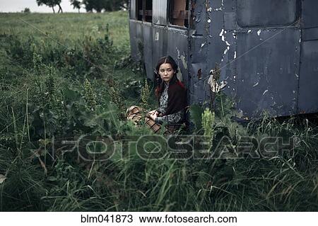 Stock Image - Caucasian woman sitting near remote field. Fotosearch