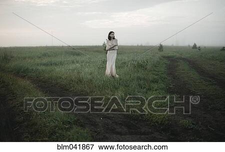 Stock Photo - Caucasian woman standing in remote field. Fotosearch