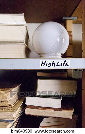 Stock Image - Close up of light bulb on shelf with books. Fotosearch