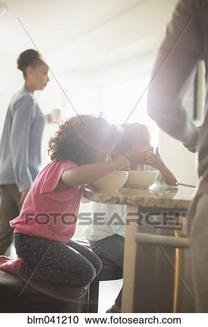 Stock Image - Family eating in kitchen. Fotosearch