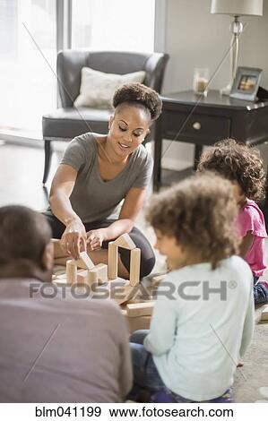 Stock Photo - Family playing with building blocks in living room. Fotosearch