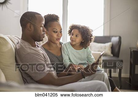 Stock Photography - Family using digital tablet on sofa. Fotosearch
