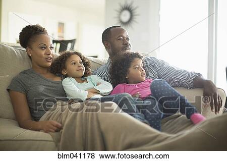 Stock Photo - Family watching television on sofa. Fotosearch