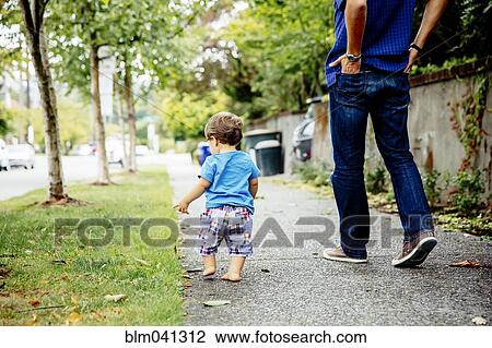 Stock Image - Father and baby son walking outdoors. Fotosearch
