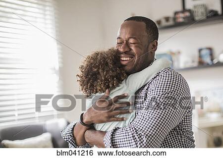 Stock Photograph - Father and daughter hugging in living room. Fotosearch