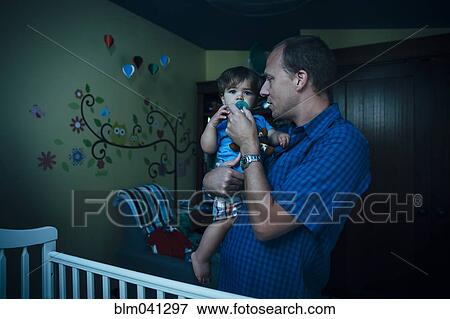 Father giving baby son pacifier in nursery View Large Photo Image Stock Photo - Father giving baby son pacifier in nursery. Fotosearch