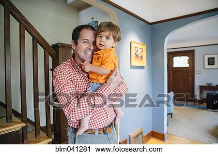 Stock Image - Father holding son at staircase. Fotosearch