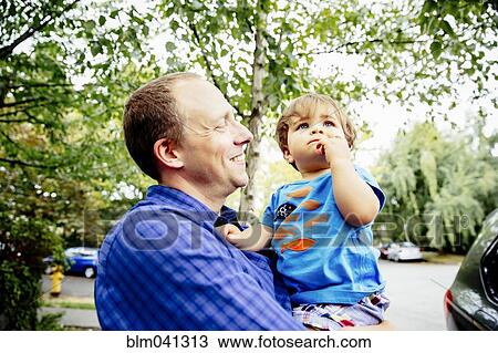 Stock Image - Father holding son outdoors. Fotosearch