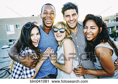 Stock Image - Friends hugging on urban rooftop. Fotosearch