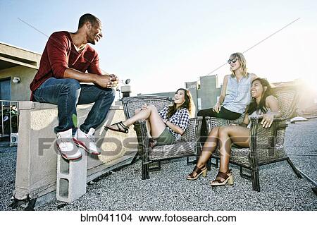 Friends relaxing on urban rooftop View Large Photo Image Picture - Friends relaxing on urban rooftop. Fotosearch