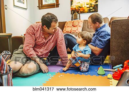 Gay fathers and baby son playing in living room View Large Photo Image Stock Photo - Gay fathers and baby son playing in living room. Fotosearch
