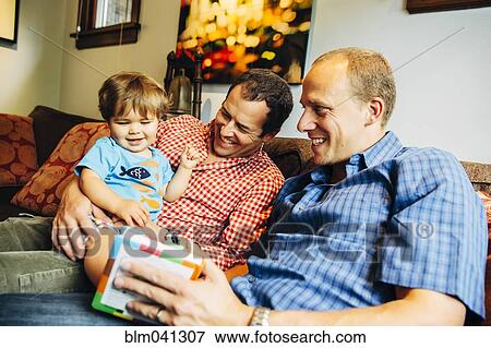 Gay fathers playing with baby son on sofa View Large Photo Image Stock Photo - Gay fathers playing with baby son on sofa. Fotosearch