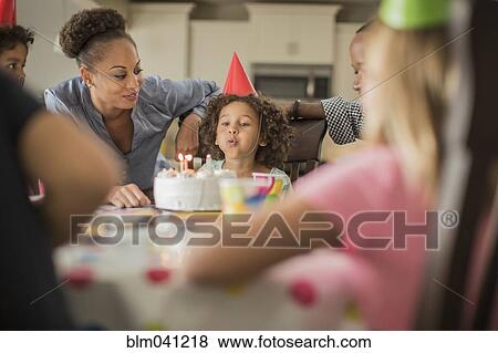 Stock Photo - Girl blowing birthday candles at party. Fotosearch