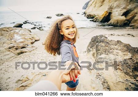 Stock Photograph - Girl pulling hand of mother on beach. Fotosearch