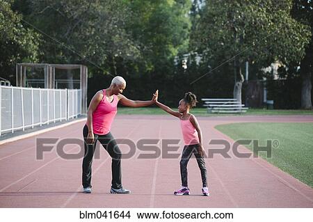 Grandmother and granddaughter high-fiving on track View Large Photo Image Picture - Grandmother and granddaughter high-fiving on track. Fotosearch