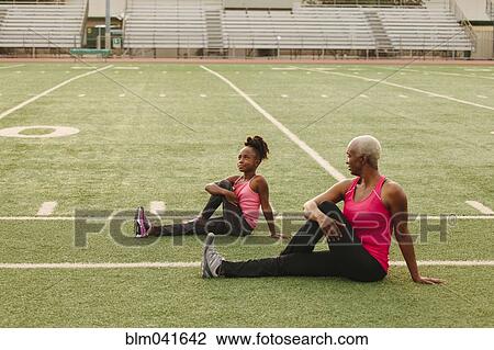 Grandmother and granddaughter stretching on football field View Large Photo Image Stock Image - Grandmother and granddaughter stretching on football field. Fotosearch