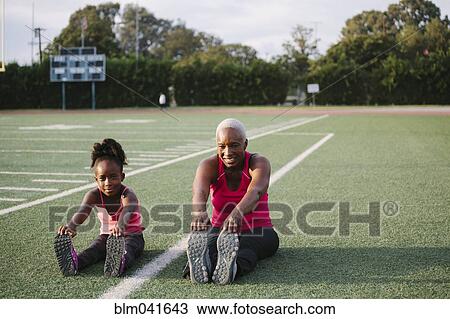 Grandmother and granddaughter stretching on football field View Large Photo Image Stock Image - Grandmother and granddaughter stretching on football field. Fotosearch