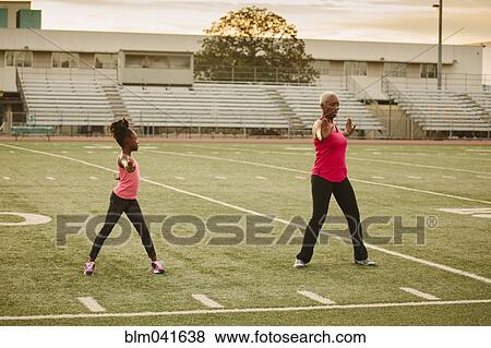 Stock Photo - Grandmother and granddaughter exercising on football field. Fotosearch