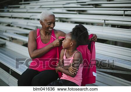 Grandmother wrapping sweater around granddaughter on bleachers View Large Photo Image Stock Photograph - Grandmother wrapping sweater around granddaughter on bleachers. Fotosearch