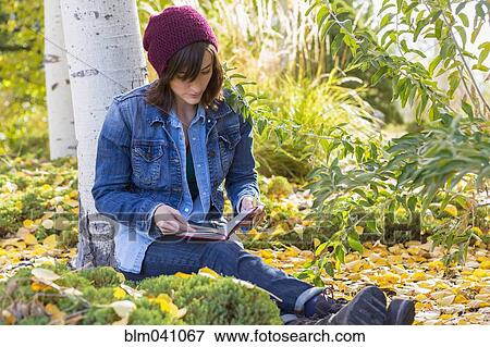 Stock Photo - Hispanic woman reading in garden. Fotosearch