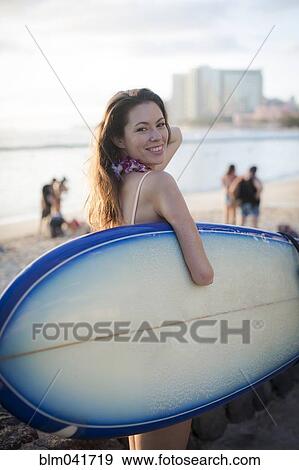 Stock Photo - Mixed race amputee carrying surfboard on beach. Fotosearch