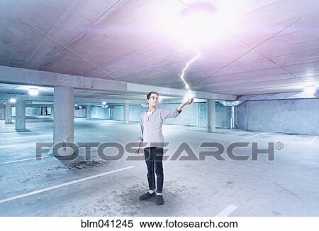 Stock Photography - Mixed race boy holding lightning in parking lot. Fotosearch