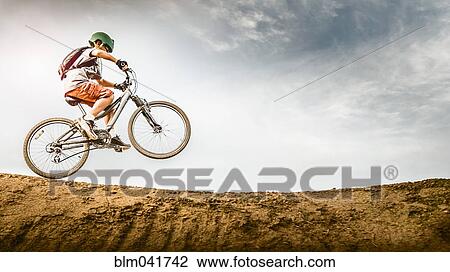 Stock Image - Mixed race boy riding dirt bike on track. Fotosearch