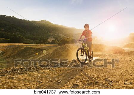 Stock Photo - Mixed race boy riding dirt bike on track. Fotosearch