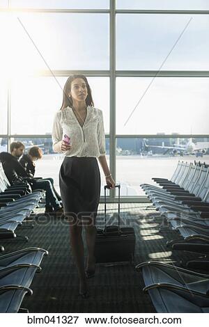 Stock Photo - Mixed race businesswoman walking in airport. Fotosearch