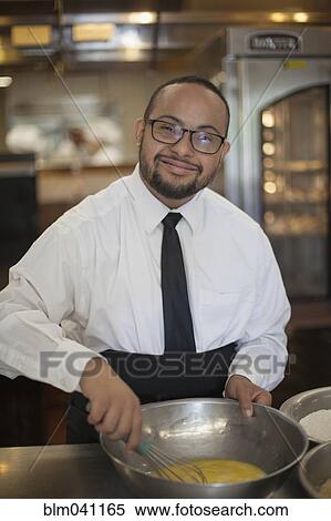 Stock Photography - Mixed race chef with down syndrome cooking in restaurant. Fotosearch