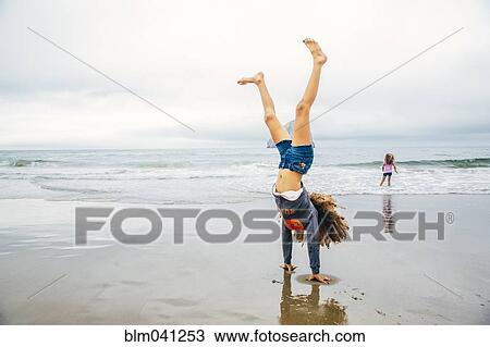 Mixed race girl doing handstand on beach View Large Photo Image Stock Image - Mixed race girl doing handstand on beach. Fotosearch