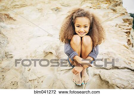 Mixed race girl hugging knees on rock View Large Photo Image Stock Image - Mixed race girl hugging knees on rock. Fotosearch