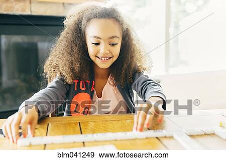 Stock Photo - Mixed race girl playing with dominoes. Fotosearch