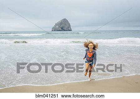 Stock Image - Mixed race girl running on beach. Fotosearch
